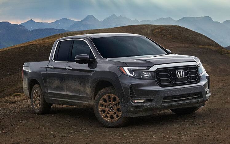 Front passenger-side view of the 2023 Honda Ridgeline RTL-E in Modern Steel Metallic with available HPD™ Bronze Package shown parked in a rugged landscape.